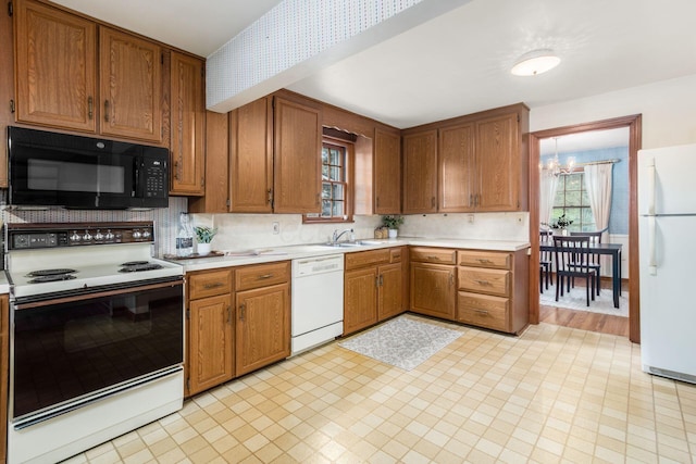 kitchen with white appliances, light countertops, a sink, brown cabinets, and wallpapered walls