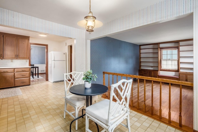 dining room with wallpapered walls, baseboards, and light flooring