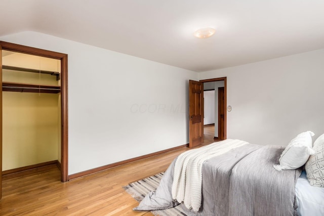 bedroom featuring light wood finished floors, baseboards, and a closet