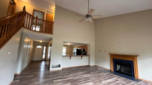 5332 Wadley Ct, Canal Winchester, OH 43110 - unfurnished living room with wood finished floors, a ceiling fan, a fireplace, a towering ceiling, and stairs