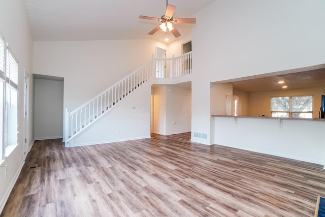 5332 Wadley Ct, Canal Winchester, OH 43110 - unfurnished living room with healthy amount of natural light, stairs, high vaulted ceiling, wood finished floors, and a ceiling fan