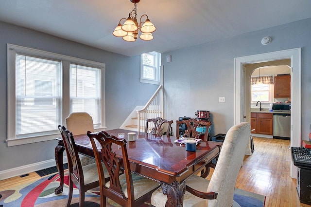 1306-1308 Wilson Ave, Columbus, OH 43206 - dining area featuring a chandelier, stairs, light wood finished floors, arched walkways, and baseboards
