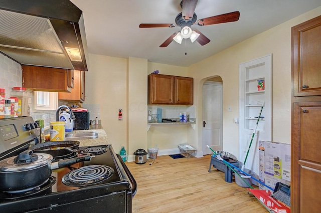 1306-1308 Wilson Ave, Columbus, OH 43206 - kitchen featuring electric range, wall chimney range hood, arched walkways, light wood-style flooring, and ceiling fan