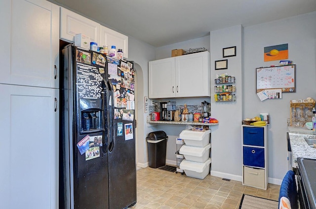 1306-1308 Wilson Ave, Columbus, OH 43206 - kitchen featuring black fridge with ice dispenser, white cabinetry, baseboards, and light stone counters