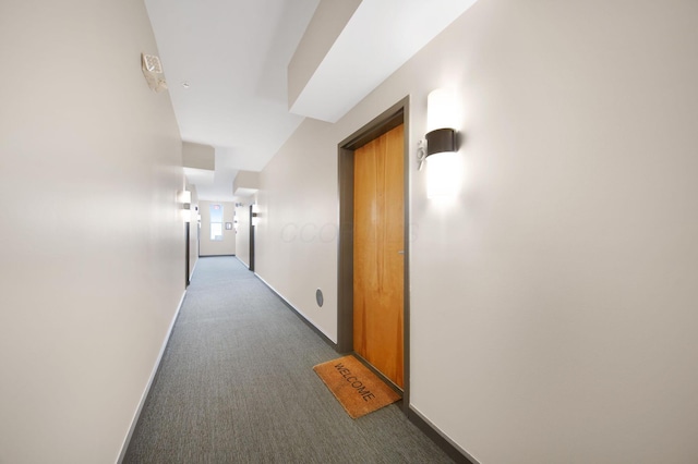 corridor with dark colored carpet and baseboards
