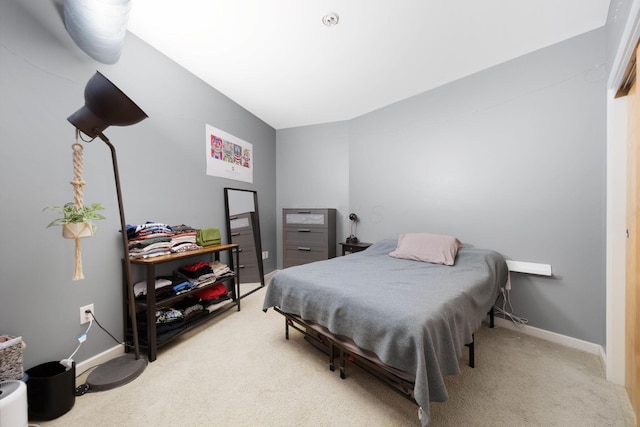 bedroom featuring light colored carpet, baseboards, and vaulted ceiling