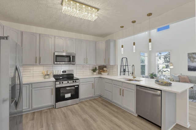 3907 Winding Path Dr, Canal Winchester, OH 43110 - kitchen with stainless steel appliances, a sink, a peninsula, light wood-style floors, and decorative backsplash