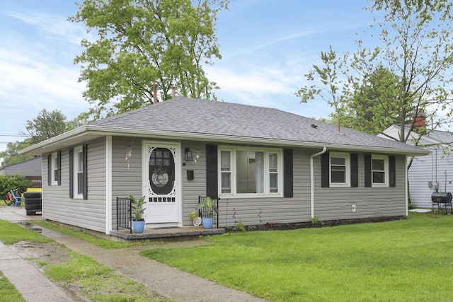 view of front of house featuring a front lawn and a shingled roof