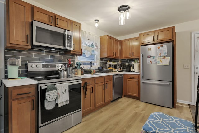 kitchen with appliances with stainless steel finishes, decorative backsplash, light countertops, and light wood-style flooring
