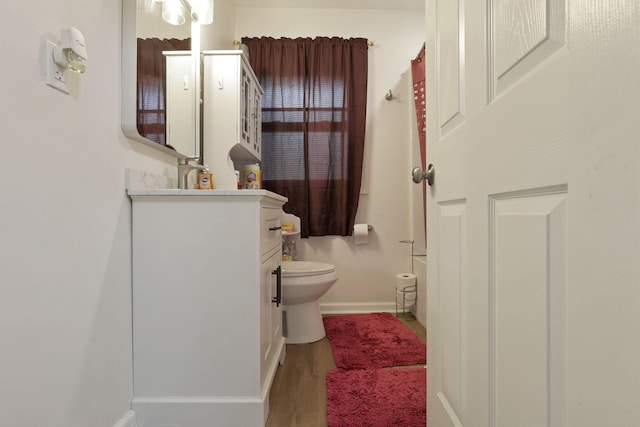 full bathroom featuring vanity, toilet, baseboards, and wood finished floors