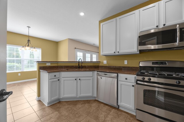 9032 Polaris Lakes Dr, Columbus, OH 43240 - kitchen with appliances with stainless steel finishes, a peninsula, a sink, decorative light fixtures, and white cabinets