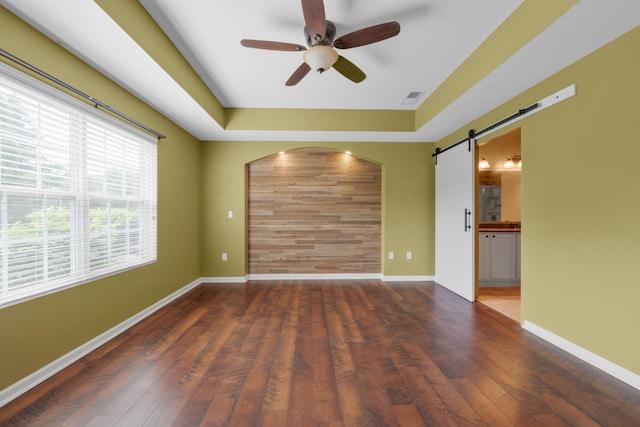 9032 Polaris Lakes Dr, Columbus, OH 43240 - empty room with a barn door, a ceiling fan, a raised ceiling, wood finished floors, and baseboards