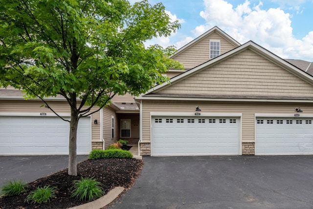 9032 Polaris Lakes Dr, Columbus, OH 43240 - view of front of home with stone siding, asphalt driveway, and a garage