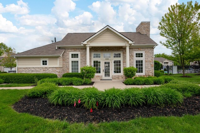 9032 Polaris Lakes Dr, Columbus, OH 43240 - back of property featuring stone siding, a chimney, french doors, and a shingled roof