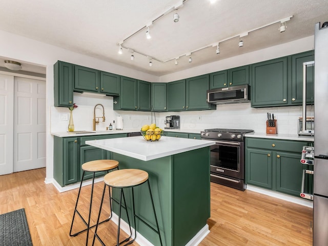 1249 Sea Shell Dr, Westerville, OH 43082 - kitchen with stainless steel appliances, green cabinetry, a sink, light countertops, and a kitchen island