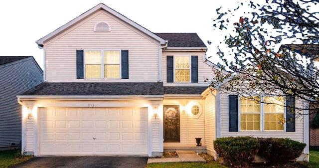 traditional-style house featuring driveway, a garage, and roof with shingles