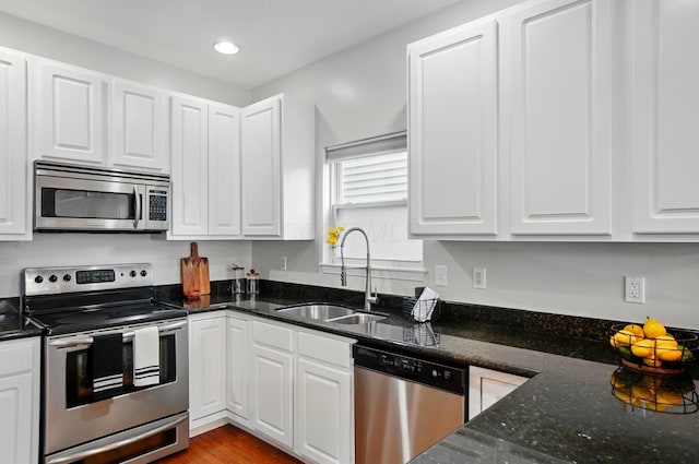 1077 Michigan Ave Unit 9, Columbus, OH 43201 - kitchen with stainless steel appliances, a sink, white cabinets, recessed lighting, and dark stone counters