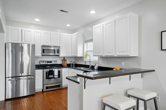 1077 Michigan Ave Unit 9, Columbus, OH 43201 - kitchen featuring appliances with stainless steel finishes, a sink, a peninsula, a kitchen bar, and dark countertops