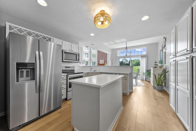 7257 Scioto Pkwy, Powell, OH 43065 - kitchen with stainless steel appliances, a chandelier, a peninsula, a center island, and light wood-type flooring