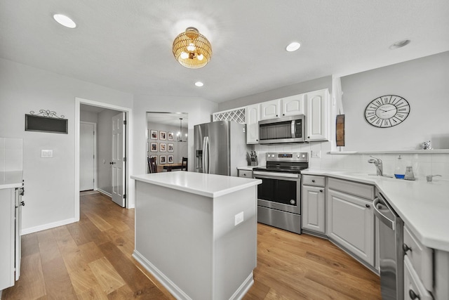 7257 Scioto Pkwy, Powell, OH 43065 - kitchen with appliances with stainless steel finishes, a sink, a kitchen island, light wood-type flooring, and light countertops