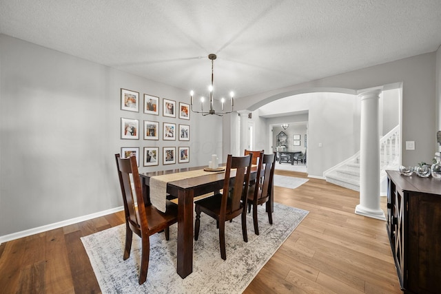 7257 Scioto Pkwy, Powell, OH 43065 - dining space featuring arched walkways, a chandelier, stairway, light wood finished floors, and ornate columns