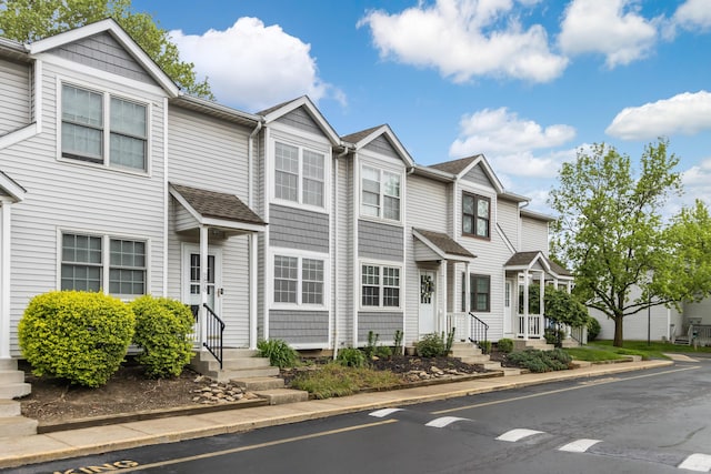 multi unit property with entry steps, a residential view, and roof with shingles