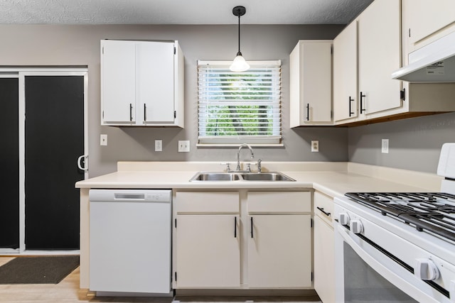 kitchen featuring white appliances, a sink, under cabinet range hood, light countertops, and white cabinetry