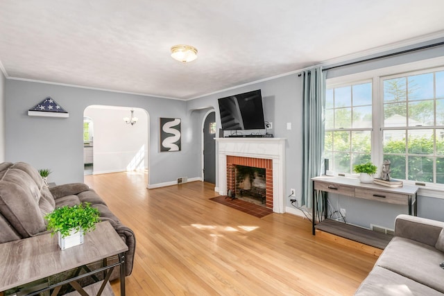 living area with arched walkways, wood finished floors, plenty of natural light, and crown molding