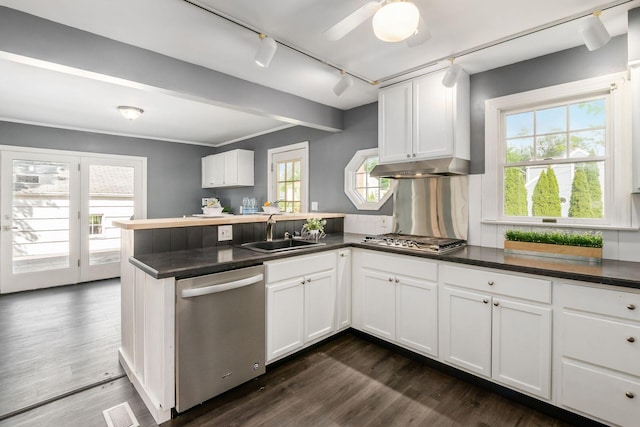 kitchen with stainless steel appliances, a sink, a peninsula, and dark countertops