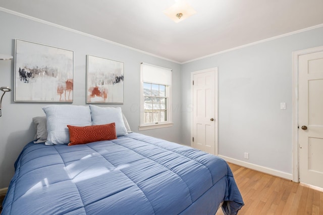 bedroom featuring light wood-type flooring, ornamental molding, and baseboards