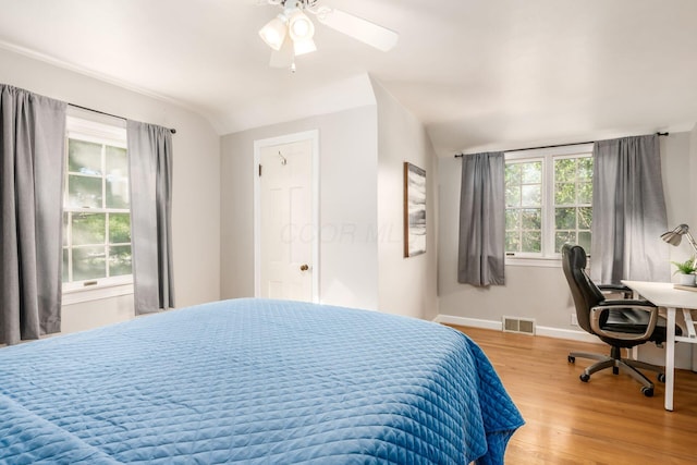 bedroom with wood finished floors, baseboards, a ceiling fan, and an office area