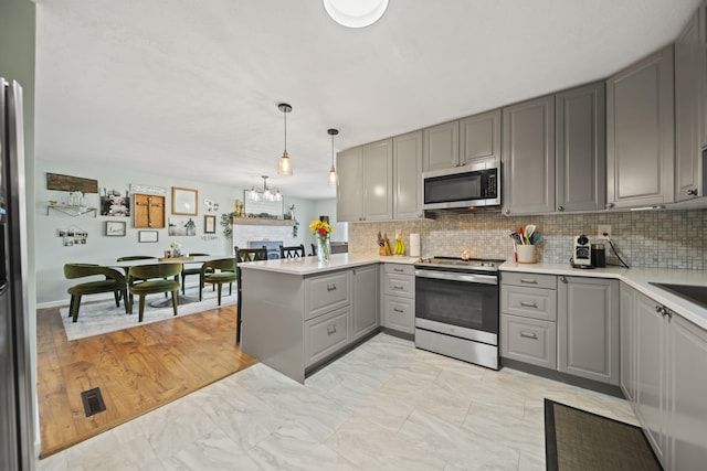 kitchen featuring gray cabinetry, appliances with stainless steel finishes, tasteful backsplash, and light countertops