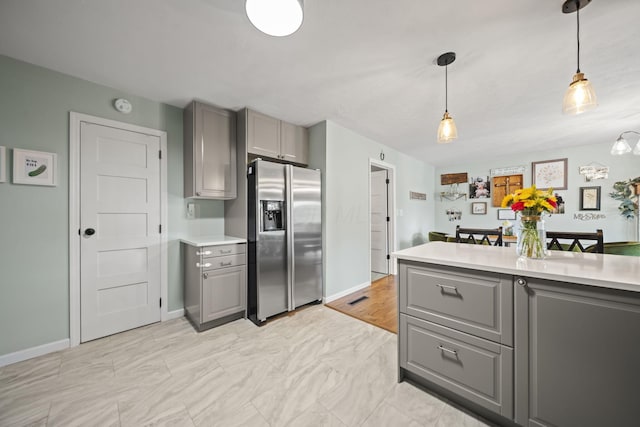 kitchen with stainless steel fridge with ice dispenser, gray cabinets, and light countertops