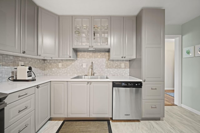 kitchen featuring dishwasher, a sink, and gray cabinetry