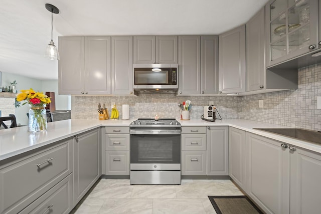 kitchen featuring stainless steel appliances, gray cabinets, decorative backsplash, light countertops, and glass insert cabinets