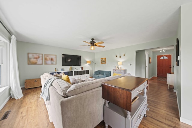living room with ceiling fan, baseboards, and light wood-type flooring