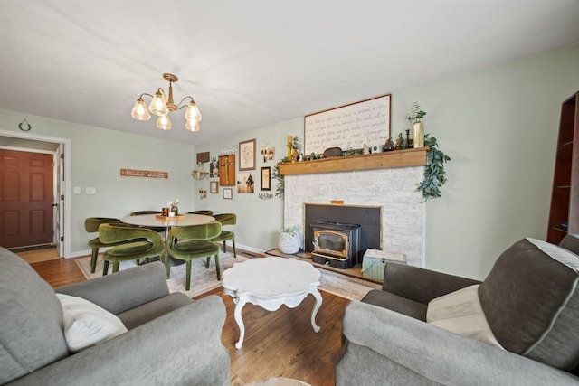 living room with a wood stove, wood finished floors, a chandelier, and baseboards