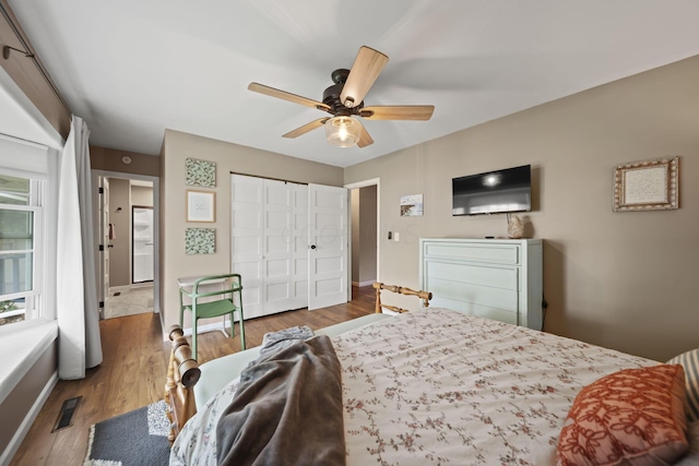 bedroom featuring baseboards, wood finished floors, a closet, and a ceiling fan