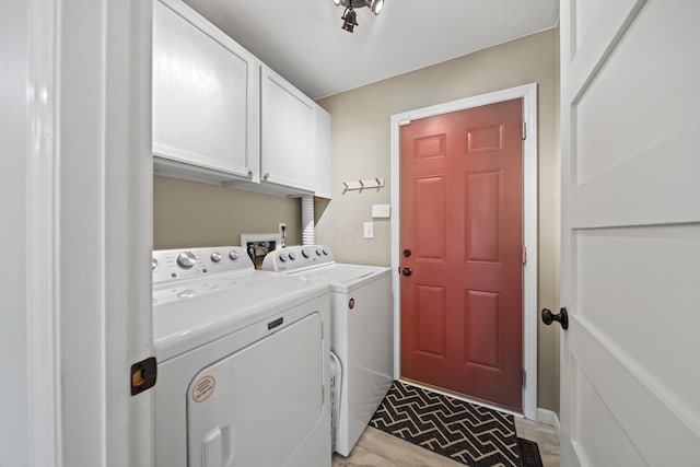 clothes washing area featuring washing machine and dryer and cabinet space