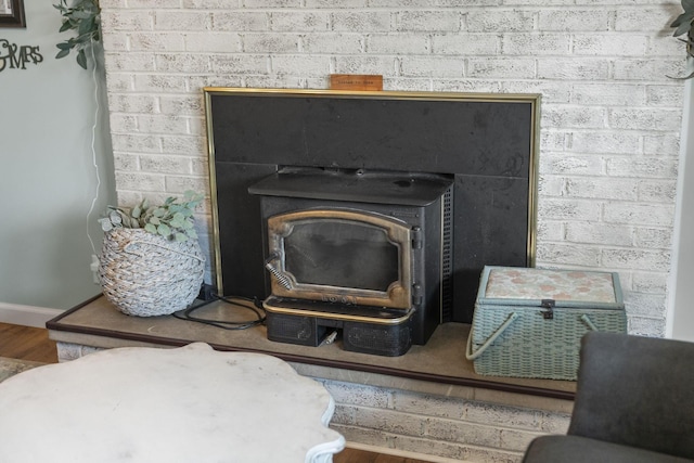 detailed view of a wood stove, wood finished floors, and baseboards