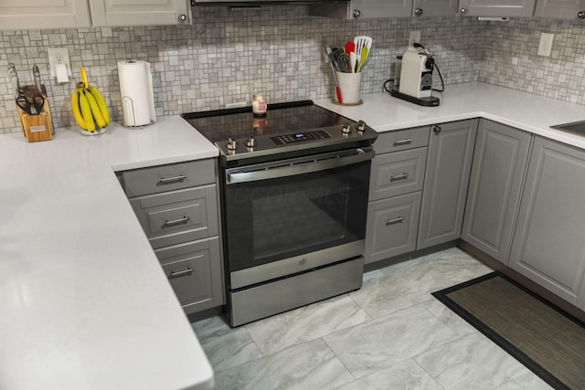 kitchen featuring gray cabinets, stainless steel electric range, backsplash, and light countertops