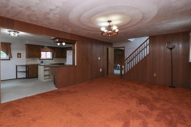 1294 Kings Corners Rd E, Mansfield, OH 44904 - unfurnished living room featuring carpet, wooden walls, a chandelier, a sink, and stairs