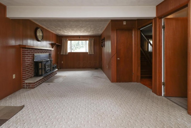 1294 Kings Corners Rd E, Mansfield, OH 44904 - unfurnished living room featuring wood walls, a wood stove, carpet floors, stairway, and beam ceiling