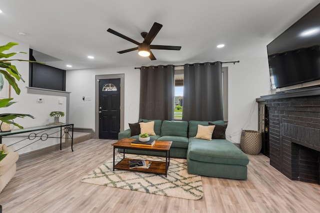 living area featuring wood finished floors, a brick fireplace, ceiling fan, and recessed lighting