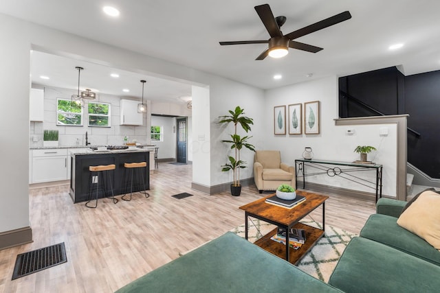 living room featuring a ceiling fan, baseboards, light wood-type flooring, and recessed lighting