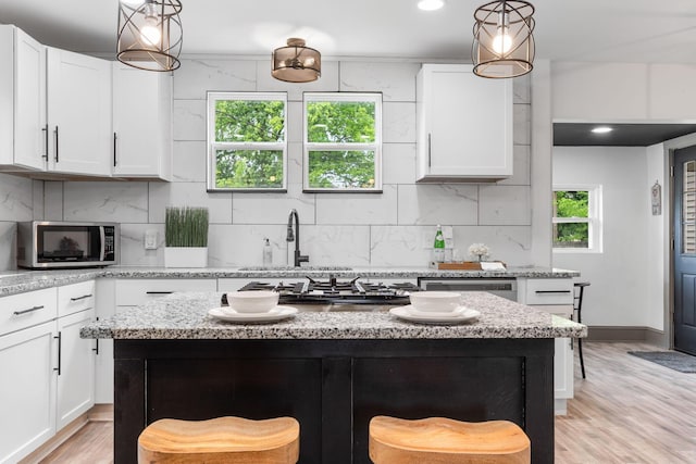 kitchen with stainless steel appliances, tasteful backsplash, white cabinets, a kitchen bar, and recessed lighting