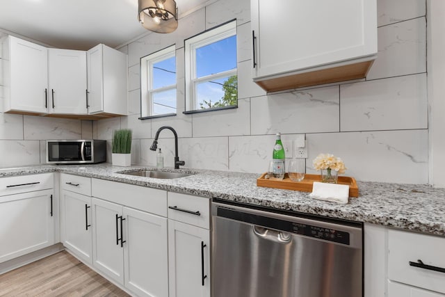 kitchen featuring stainless steel appliances, a sink, decorative backsplash, and white cabinets