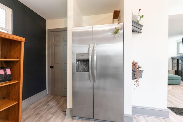 kitchen featuring stainless steel fridge with ice dispenser, light wood-type flooring, and baseboards