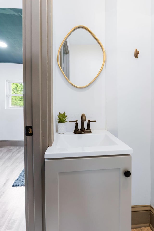 bathroom with vanity, wood finished floors, and baseboards