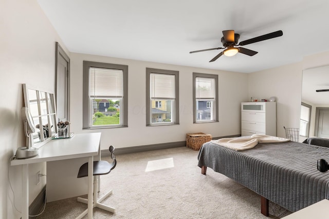 carpeted bedroom with a desk, baseboards, and a ceiling fan